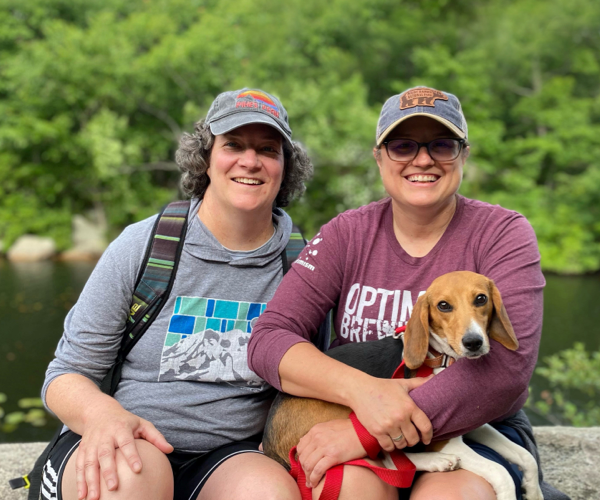 Butter the beagle sitting with two women outside